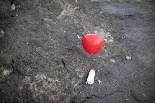 Red ball flies over asphalt. Balloon outside. Inflatable ball against background of road.