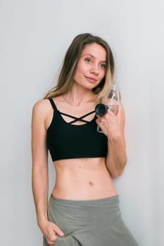 Sporty young woman drinking water after training at home. Active lifestyle and wellness