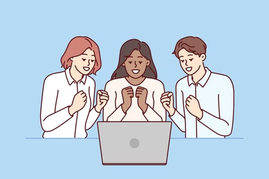 Team of excited friends sitting near laptop and watching football match together. Team of man and two girls watch video broadcast and clench fists, wanting to hear important news via video link
