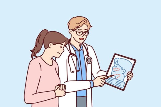 Man plastic surgeon consults woman patient demonstrating tablet with ways to tighten skin on face to get rid of wrinkles. Girl turned to plastic surgeon for help to do facial surgery