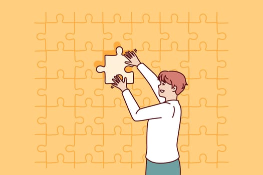 Business man putting last piece of puzzle in free space for problem solving concept. Guy in business clothes is engaged in obtaining new skills and performs complex challenge on instructions manager