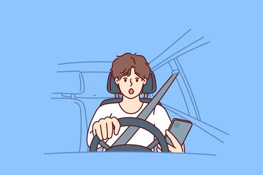 Distracted man driver with phone sits behind wheel of car and gets scared sees obstacle on road or sharp turn. Shocked driver not following traffic rules using smartphone while driving
