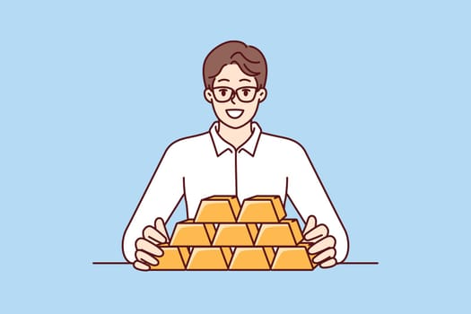 Businessman with gold bars sitting at table and smiling looking at camera for precious metals investment. Man investor with gold bars avoiding inflation and symbolizing diversification of assets