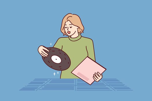 Woman chooses vinyl record standing in store for retro music collectors and analog audio lovers. Girl is looking for classical music from favorite composer at used vinyl record fair