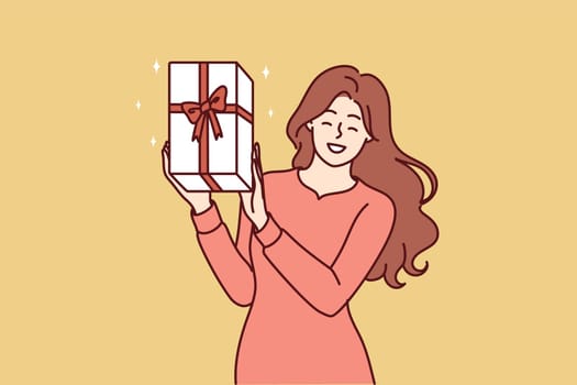 Happy woman shows gift box with red ribbon given by boyfriend in honor of birthday or christmas eve. Positive girl shows off gift she received after participating in promotion from clothing store
