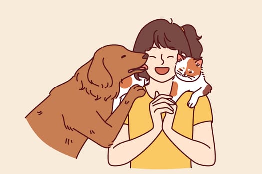 Little girl with pets enjoys communicating with cat sitting on shoulder and dog licking face. Teenage girl laughs rejoicing at presence of pets and makes friends with kitten and puppy