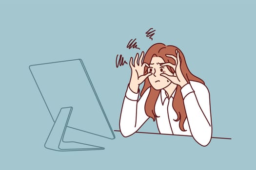 Sleepy businesswoman trying to stay awake sitting at workplace with monitor is feeling tired due to overwork. Businesswoman doing office work suffering from vision problems and strict deadlines