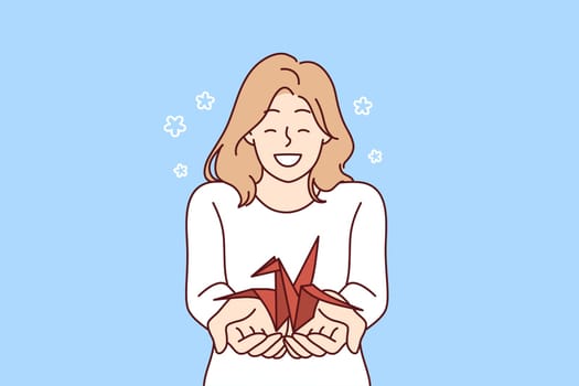 Woman with origami crane in palms wants to draw attention to problem of wildlife and extinction of animals from red book. Positive smiling girl holding origami bird for creative hobby concept