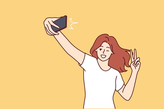 Woman laughs taking selfie and showing peace sign to post photo on social network or dating site. Positive girl blogger doing gesture with fingers recording selfie video for subscribers