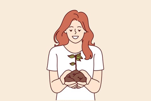 Woman holds handful of earth with plant drawing attention to problem of ecology and pollution or CO2 emissions. Happy girl doing plant cultivation and care for environment or ecology as volunteer