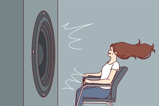 Deafened woman near giant subwoofer from music center listening to loud rhythmic track with bass sitting in chair. Subwoofer with round speaker produces loud sound waves for girl who loves rock songs