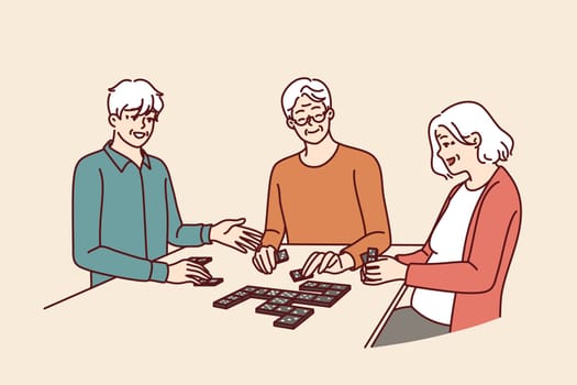 Elderly people play dominoes undergoing rehab at nursing home or having sunday get-together with friends. Men and women are sitting at table enjoying game of dominoes with former colleagues