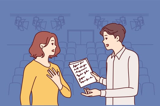 Man and woman working as actors are rehearsing theatrical performance standing on stage. Guy and girl are memorizing text of theatrical performance, wanting to receive award for acting