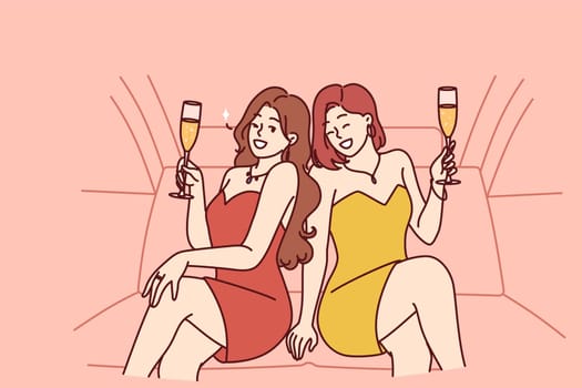 Celebrity women sit in luxury car with glasses filled with sparkling wine during pre-wedding bachelorette party. Celebrity girls in evening dresses riding in limousine enjoy premium atmosphere