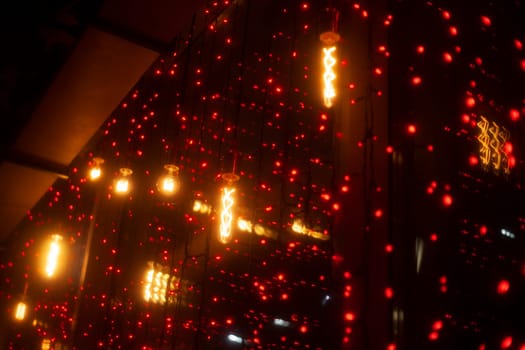 Red garlands on glass. Interior details. Window garland decoration. Lights in dark.