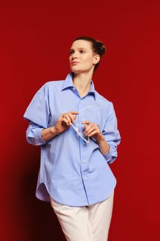 Low angle view of classy woman in cotton shirt and trousers holding in hands her sunglasses