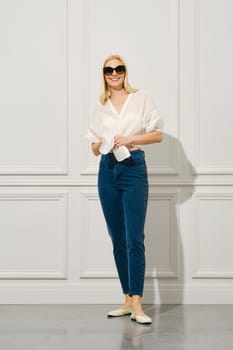 Cheerful woman in sunglasses ties shirt at her waist