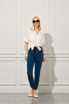Trendy adult woman walks in the room in jeans and shirt tied at her waist