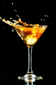 alcohol splash in martini glass on black background