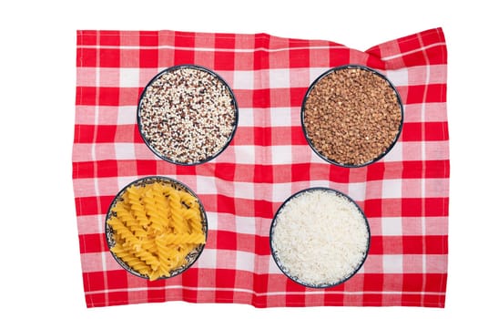Vegetable food. Closeup of four bowls with buckwheat, noodles, rice and quinoa on a red checkered tablecloth isolated. Healthy eating and nutrition. Top view with space.
