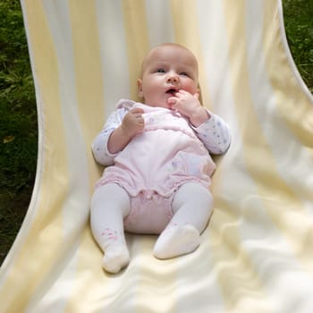 Baby girl relaxing  in striped hammock on a summer day
