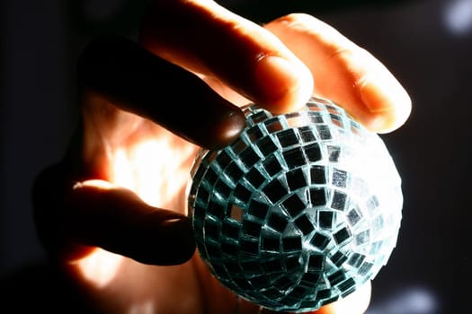 hand take a disco mirror ball in fingers