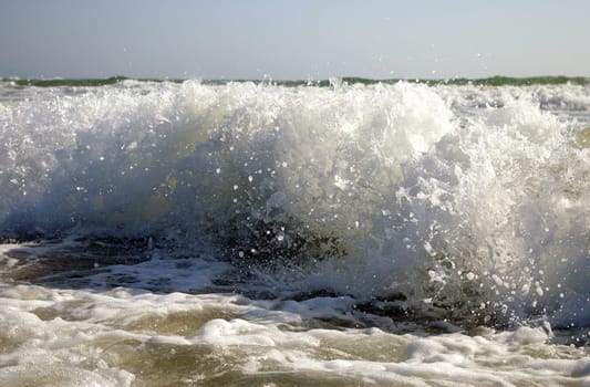 Blanching spume of the sea wave wears down on sandy coast.