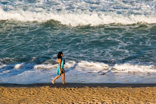 Young woman walking along Black Sea beach in Obzor, Bulgaria, in evening light