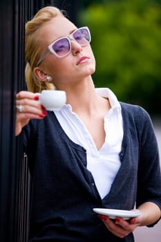 Blond lovely young woman drinking coffee outside