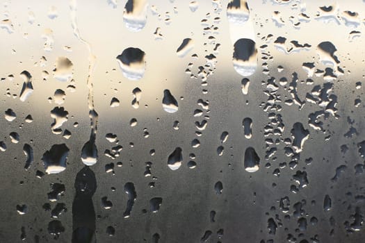 Fine and large water drops on morning window glass