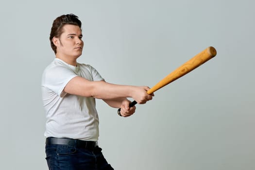 A man with a bat in his hands swings on a gray background. High quality photo