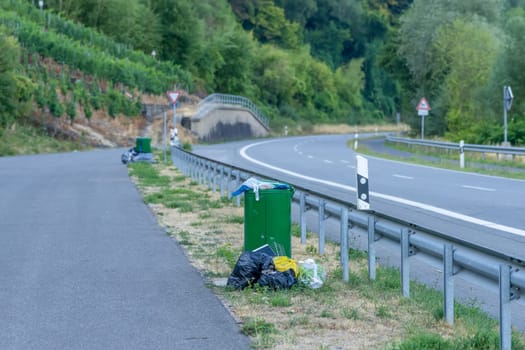 An overflowing rubbish bin at the roadside shows problems with disposal. Possible causes are strikes or other difficulties