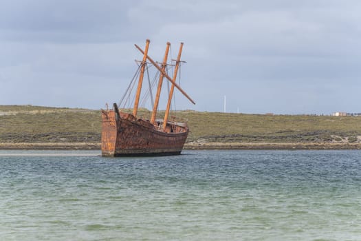 An old whaler wreck in Whalebone Cove off Stanley in the Falkland Islands. Stanley in the background