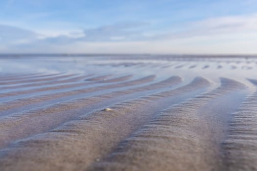 Wave-like patterns in the shallows on the shore of the Baltic Sea against a blue sky. A breathtaking natural phenomenon captured in one photo