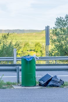 An overflowing rubbish bin at the roadside shows problems with disposal. Possible causes are strikes or other difficulties