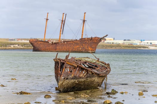 An old whaler wreck in Whalebone Cove off Stanley in the Falkland Islands. Stanley in the background