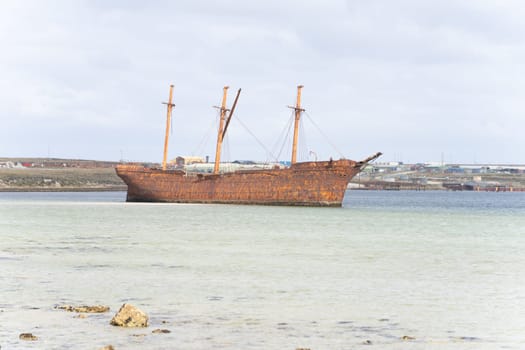 An old whaler wreck in Whalebone Cove off Stanley in the Falkland Islands. Stanley in the background
