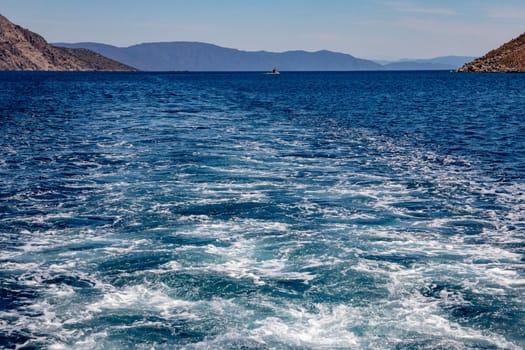 Trail on water surface or powerful stern wave behind of fast moving speedboat or ferry while cruising on ocean. Greek Aegean.