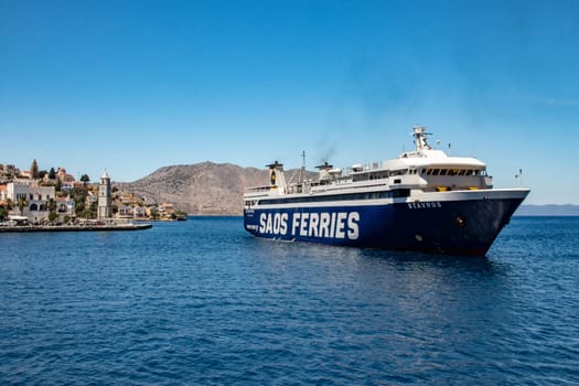 SYMI, Greece - JUN 03, 2021. A large ferry docking in the pictorial harbour on the Greek island of Symi island in Greece. Dodecanese.
