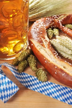 original Bavarian XXL Oktoberfestbreze with beer jug,hops and wheat in front of old holtbrettern