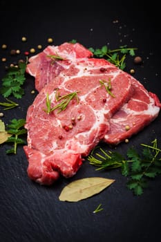 Fresh raw meat on black board with spices and herbs