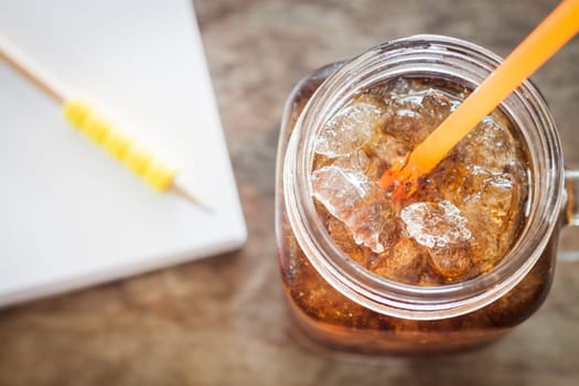 Glass of cola with ice on wooden table, stock photo