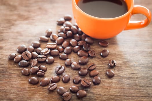 Coffee beans with coffee cup on wooden table, stock photo