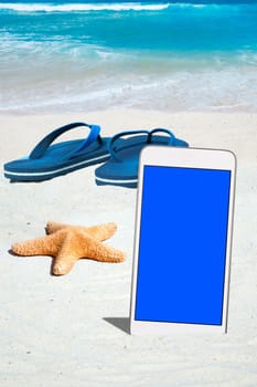 Smartphone,flip flops and starfish on the beach