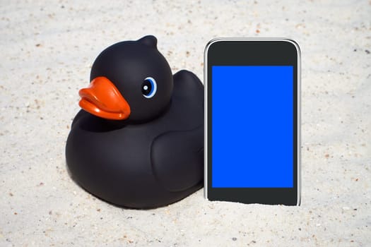 Black rubber duck and smartphone on the beach