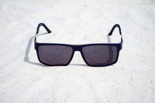 Individual sunglasses are located on the sandy beach