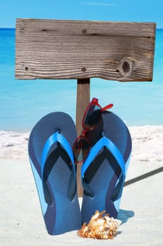 Flip flops,sunglasses and empty wooden sign on the beach