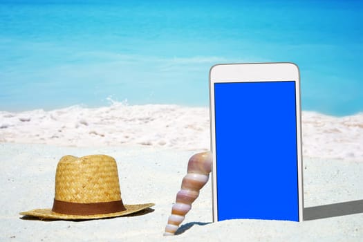 White smartphone and straw hat on the sandy beach