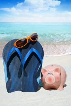 Pink piggy bank,flips flops and sunglasses on the beach