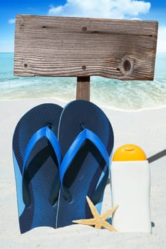 Flip flops,sunmilk and empty wooden sign on the beach